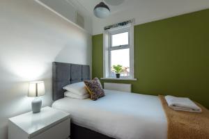 - une chambre verte avec un lit blanc et une fenêtre dans l'établissement Comfortable and convenient stay 3 bed house, à Southampton