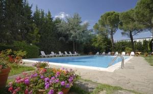 una piscina con sedie e fiori in un cortile di Hotel First a Calenzano