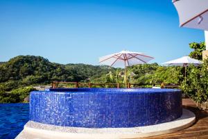 een blauwe tafel met stoelen en parasols naast het water bij Hotel El Copal in Mazunte