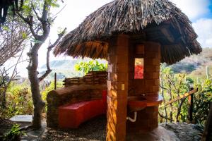 een kleine hut met een rode bank ervoor bij Hotel El Copal in Mazunte