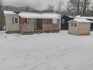 une maison avec de la neige devant elle dans l'établissement Grand Mobil Home 6 personnes climatisé avec 3 chambres et 2 salles de bains à Munster en Alsace, à Munster