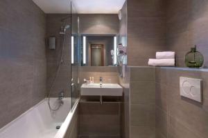 een badkamer met een bad, een wastafel en een douche bij Best Western Plus Hotel Du Parc Chantilly in Chantilly