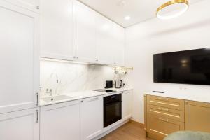 a kitchen with white cabinets and a flat screen tv at Lux Apartment With A Terrace In Vilnius Old Town in Vilnius