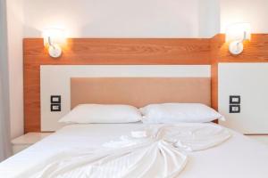 een wit bed met 2 witte kussens en 2 verlichting bij Ventus Hotel in Ksamil