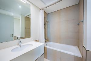 La salle de bains est pourvue d'un lavabo, d'une baignoire et d'un miroir. dans l'établissement Expo Village Serviced Apartments, à Dubaï