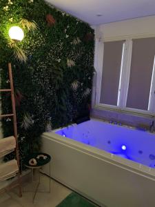 een badkamer met een blauw bad naast een groene muur bij L'extasia appartement,spa jacuzzi Grenoble in Grenoble