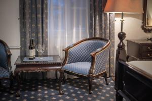 プラハにあるPytloun Old Armoury Hotel Prague, Stará Zbrojniceの椅子、テーブル、ワイン1本が備わる客室です。