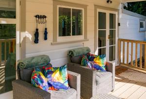 eine Veranda mit zwei Korbstühlen auf einer Veranda in der Unterkunft Birdsong Cottage in Paraparaumu