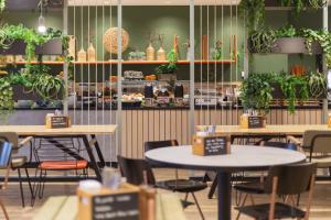 un restaurant avec des tables, des chaises et des plantes en pot dans l'établissement Holiday Inn - the niu, Amity Potsdam, an IHG Hotel, à Potsdam