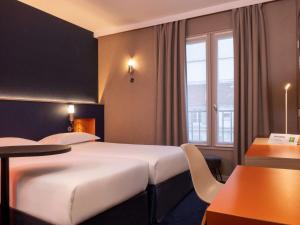 una camera d'albergo con due letti e un tavolo di ibis Styles Bourg La Reine a Bourg-la-Reine