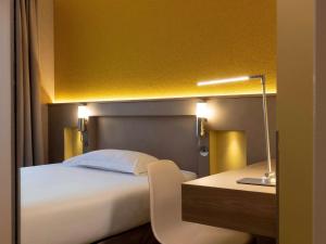 una camera con letto e scrivania con lampada di ibis Styles Bourg La Reine a Bourg-la-Reine