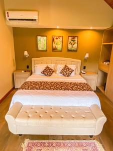 um quarto com uma cama grande e um sofá branco em Chalés Princesa Isabel em Petrópolis