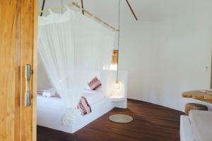 een witte kamer met een bed met gordijnen bij Mana Eco Retreat in Kuta Lombok