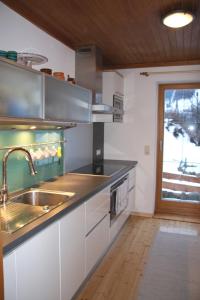 una cucina con armadi bianchi, lavandino e finestra di Chalet Sonne a Maria Alm am Steinernen Meer