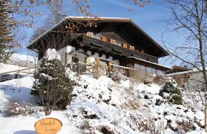 una casa coperta di neve di fronte di Chalet Sonne a Maria Alm am Steinernen Meer