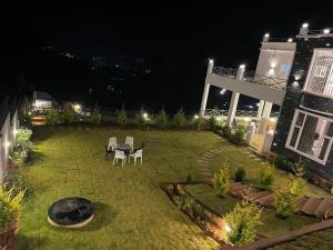 un patio trasero por la noche con mesa y sillas en Orchard Valley View Home Stay, en Ooty