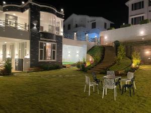 un patio con sillas y una mesa frente a una casa en Orchard Valley View Home Stay, en Ooty