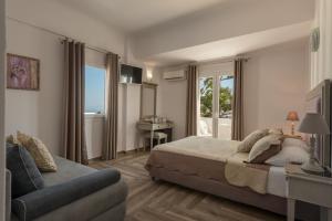 a bedroom with a bed and a couch and windows at Daedalus Hotel in Fira