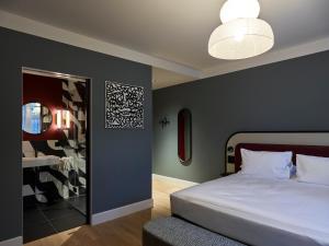 een slaapkamer met een groot wit bed en een spiegel bij Boutique Hotel Waldhaus beider Basel in Bazel