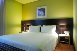 1 dormitorio con 1 cama blanca grande y paredes verdes en SANA Capitol Hotel, en Lisboa