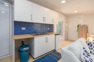 a kitchen with white cabinets and a sink and a couch at Setúbal Downtown Blue in Setúbal