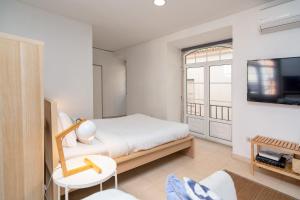 a white bedroom with a bed and a tv at Setúbal Downtown Blue in Setúbal