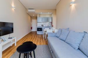 a living room with a blue couch and a kitchen at Setubal Prime in Setúbal