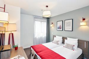 um quarto de hotel com uma cama, uma secretária e luzes em Appart'City Confort Strasbourg Centre em Estrasburgo