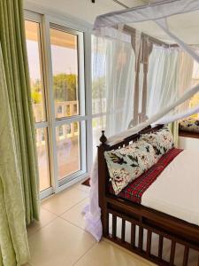 a bedroom with a canopy bed and a large window at Fiorella Beach House, Diani Beach in Diani Beach