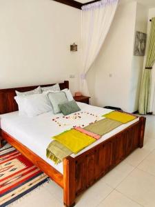 a bedroom with a wooden bed with blankets and pillows at Fiorella Beach House, Diani Beach in Diani Beach