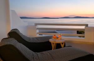 un balcón con 2 sillas y una mesa con puesta de sol en Anax Resort and Spa, en Agios Ioannis Mykonos