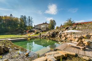 einen Pool in einem felsigen Garten mit einem Sonnenschirm in der Unterkunft Wellness & spa hotel Augustiniánský dům in Luhačovice