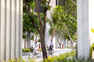 dois homens a andar de bicicleta numa rua com árvores em The Culture Samui em Bangrak Beach