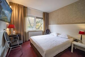 una camera d'albergo con un grande letto e una finestra di Fletcher Hotel Apeldoorn ad Apeldoorn