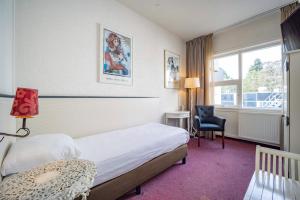 una camera d'albergo con un letto, una sedia e una finestra di Fletcher Hotel Apeldoorn ad Apeldoorn