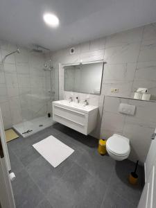 La salle de bains blanche est pourvue d'un lavabo et de toilettes. dans l'établissement Chez Gina, à Herbeumont