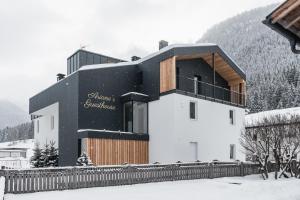 ein Gebäude im Schnee mit einem Zaun in der Unterkunft Ariane's Guesthouse in Sexten