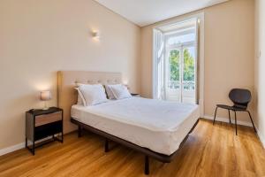 a bedroom with a bed and a chair and a window at Setubal Prime in Setúbal