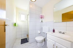 a white bathroom with a toilet and a sink at Apartments Elvir Nin in Nin