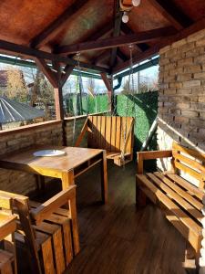 eine Terrasse mit einem Holztisch und Bänken in einem Pavillon in der Unterkunft Filigran in Palić