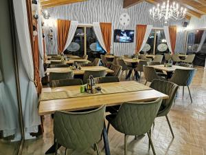 een restaurant met houten tafels en stoelen en een kroonluchter bij POPASUL LU' VODĂ in Borşa