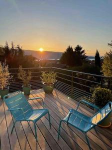 - deux chaises bleues assises sur une terrasse au coucher du soleil dans l'établissement Maison de vacances 220m2 vue Lac et Château, à Menthon-Saint-Bernard