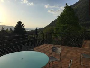 une table et des chaises blanches sur une terrasse avec des montagnes dans l'établissement Maison de vacances 220m2 vue Lac et Château, à Menthon-Saint-Bernard