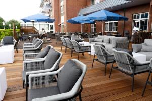 un groupe de chaises, de tables et de parasols sur une terrasse dans l'établissement Hotel Novum, à Hinte