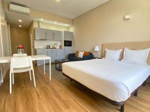 a bedroom with a large white bed and a kitchen at Setubal Prime in Setúbal