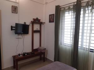 een kamer met een tv, een bed en een raam bij Tiny house for couple in Madikeri