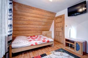 a bedroom with a bed and a wooden wall at Pokoje Pod Lasem in Kościelisko