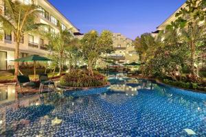 a swimming pool with chairs and umbrellas in front of a building at Bali Nusa Dua Hotel in Nusa Dua