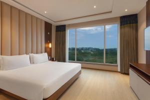 - une chambre avec un grand lit et une grande fenêtre dans l'établissement Fortune Park Airport Road, Hubballi - Member ITC's Hotel Group, à Hubli