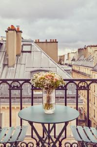 eine Vase mit Blumen auf einem Tisch auf einem Balkon in der Unterkunft Hotel Petit Lafayette in Paris